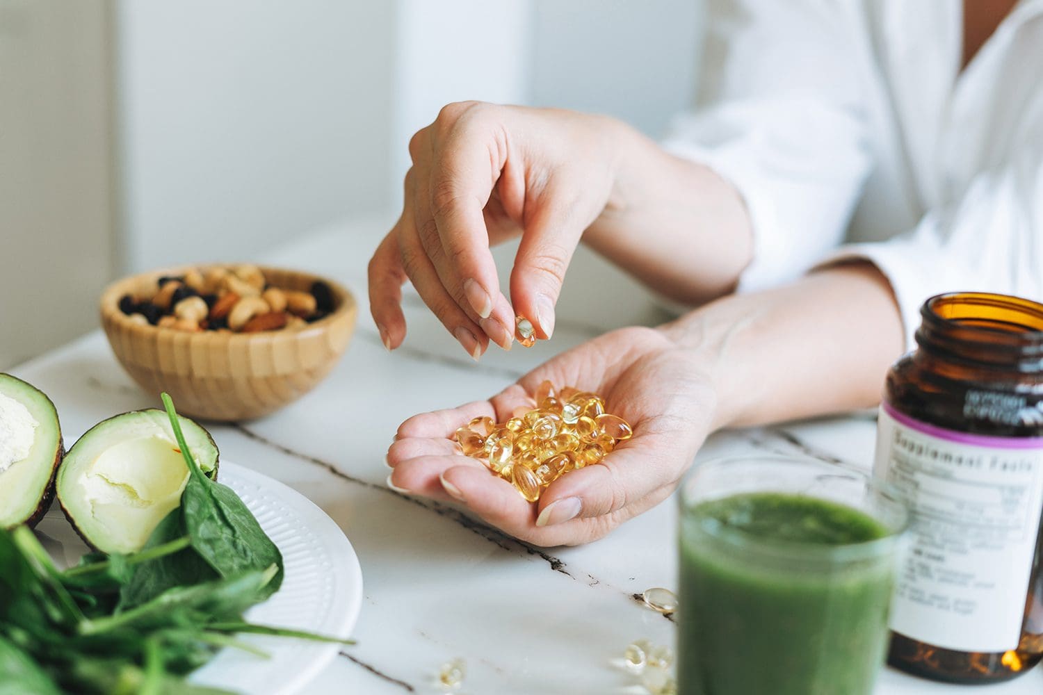 Woman doctor nutritionist hands in white shirt with omega 3, vitamin D capsules with green vegan food. The doctor prescribes a prescription for medicines and vitamins at the clinic