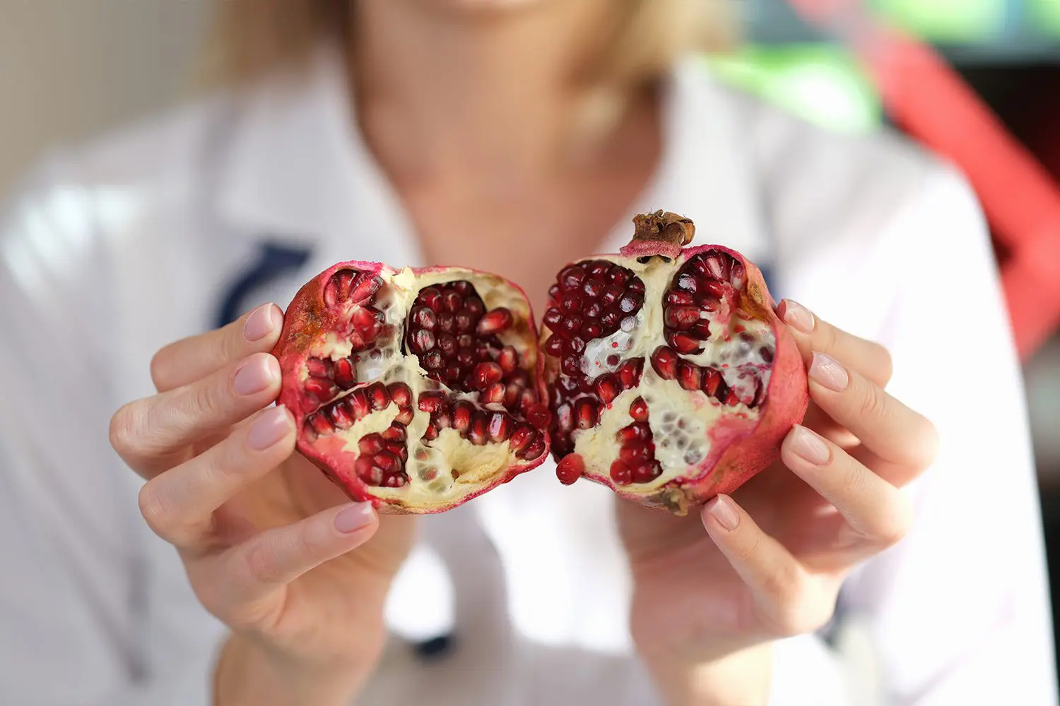 Close up, hands doctor holding ripe pomegranate fruit. Visit to a nutritionist, fruit diet, vitamin balance