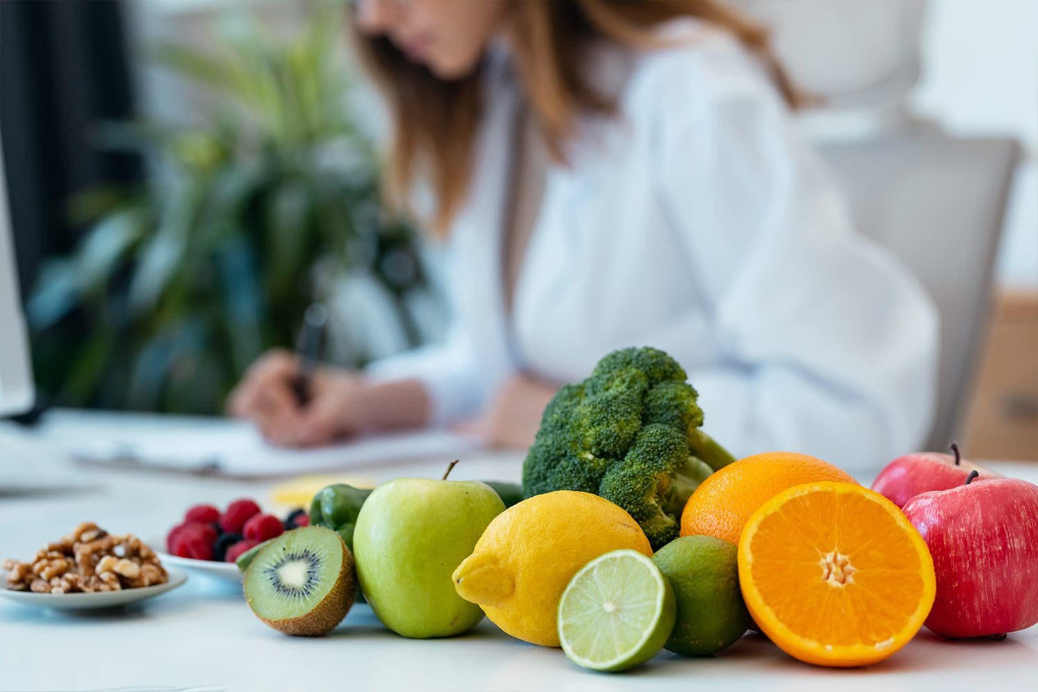 Close up of beautiful smart nutritionist woman working with computer while taking notes in the nutritionist consultation