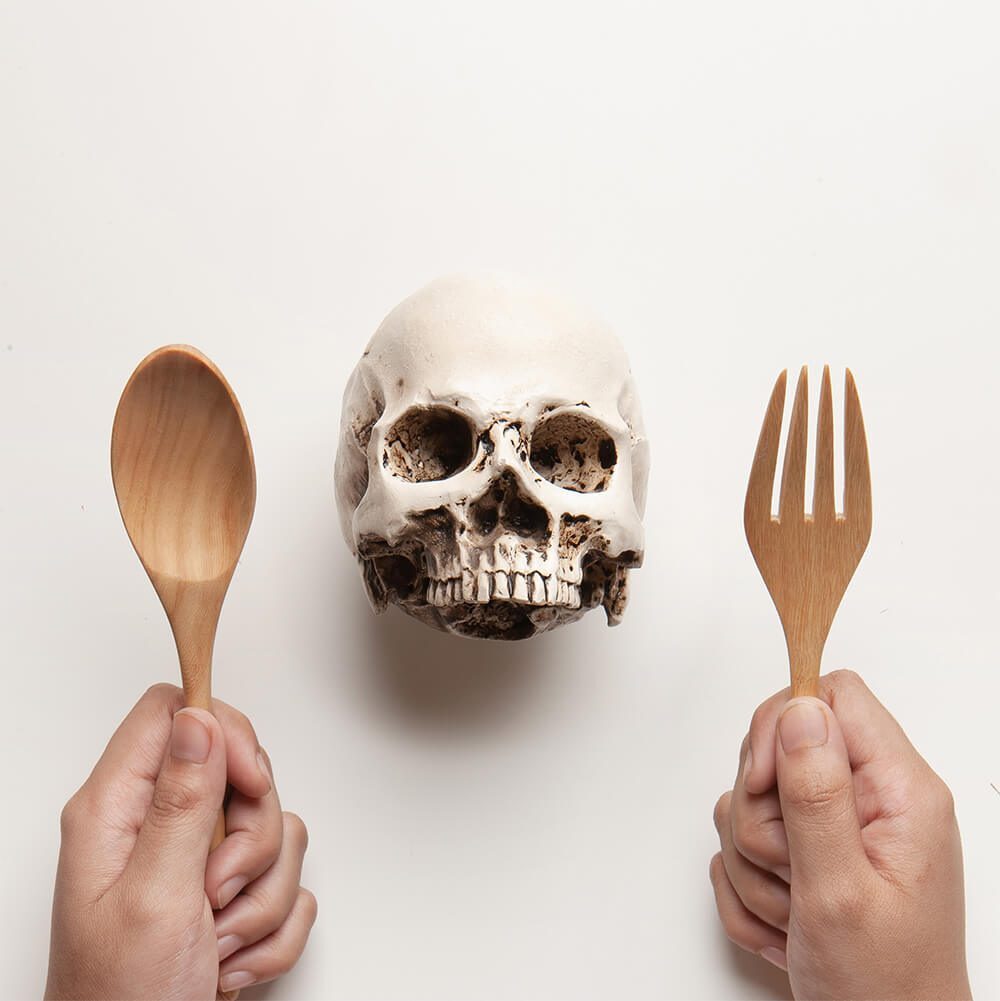 Concept of toxic food inside the human body and eating contaminated food. Eating Skull on White Background.