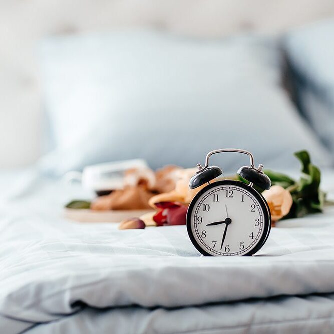 alarm clock at the morning. breakfast in bed with coffee and croissants. Healthy breakfast served on a tray on bed.